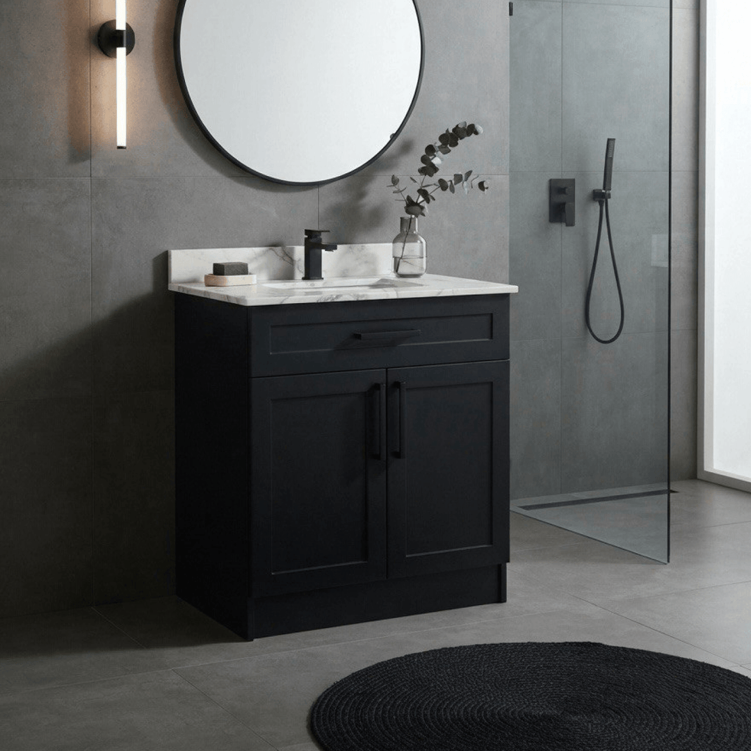 Vue d'une salle de bain contemporaine avec carrelage mural gris texturé, mettant en valeur la vanité noire mat de style shaker, un miroir rond noir