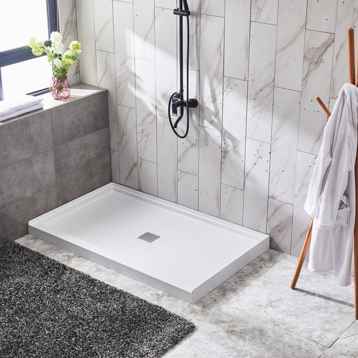 Base de douche alcove blanche installée dans une salle de bain moderne avec carrelage effet marbre et douche noire design