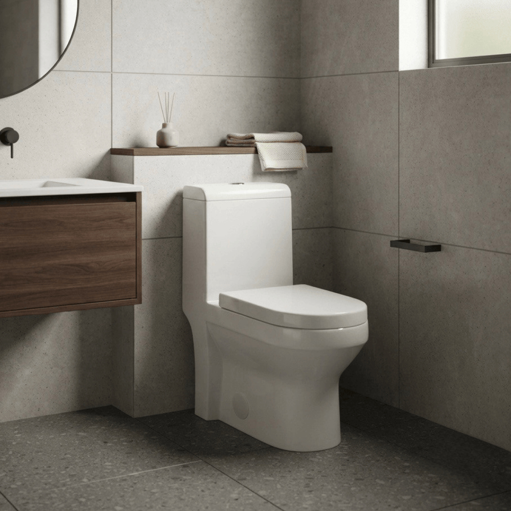 Intérieur de salle de bain minimaliste mettant en valeur une toilette monobloc moderne installée sur un plancher en céramique grise, accompagnée d'un meuble-lavabo en bois foncé et d'un miroir circulaire, créant une ambiance zen et luxueuse